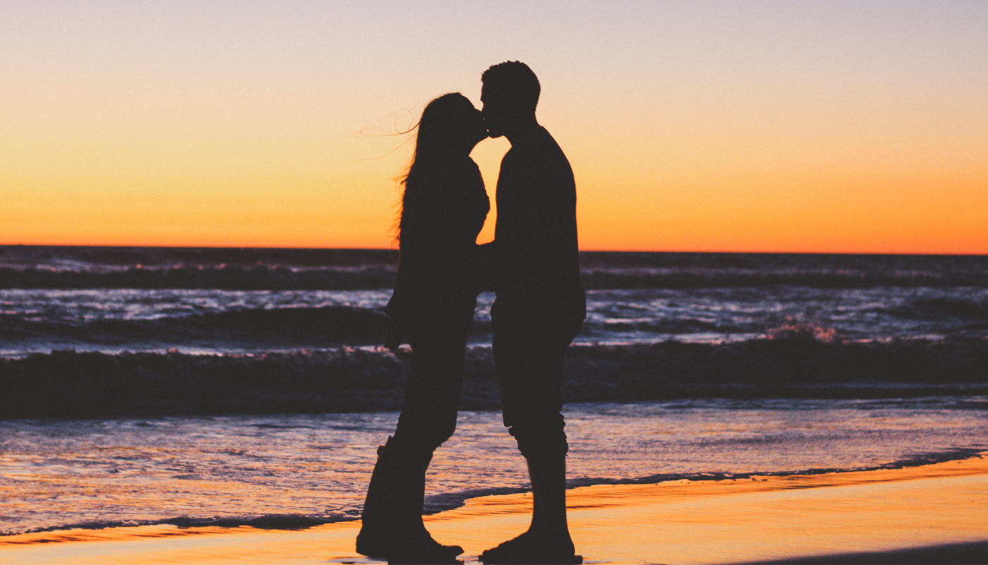 couple kissing on the beach in the winter during sunset